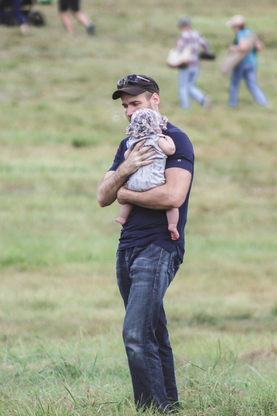 dad holding baby at outdoor sporting event