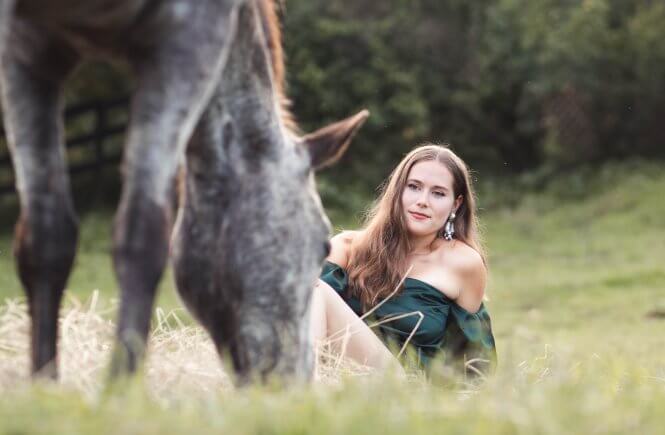 girl lying in grass next to horse