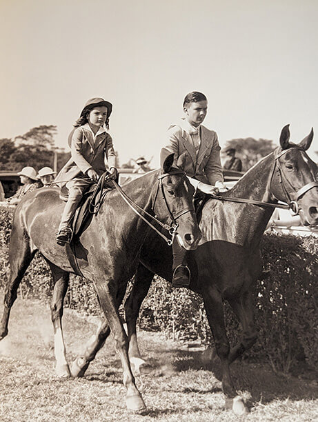 black and white photo of young Jackie Kennedy riding with a friend