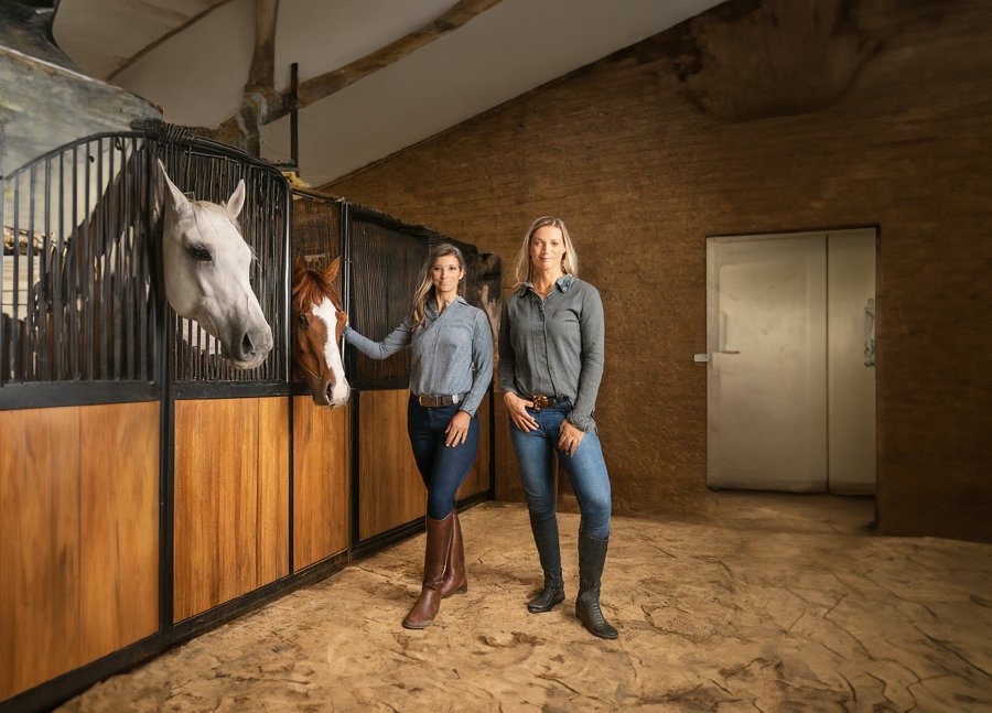 AI image of women standing in front of horse stalls.