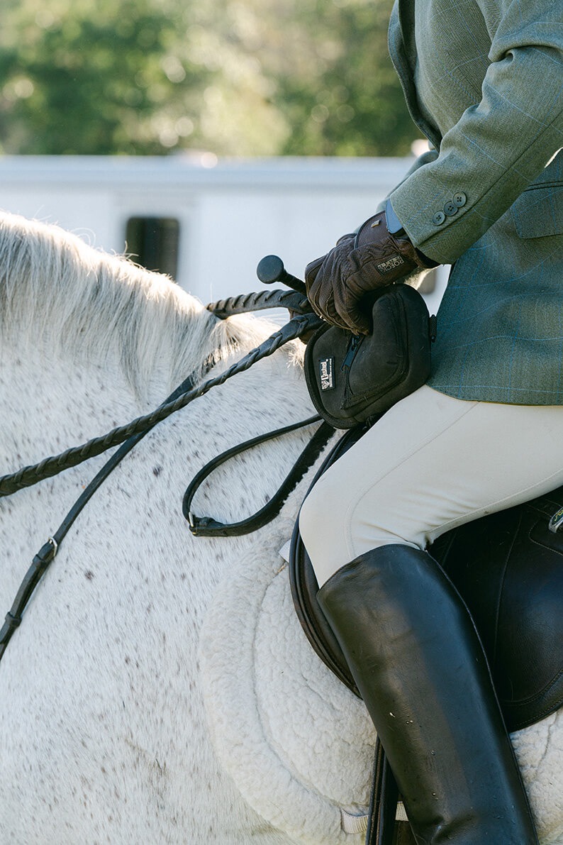 close up of a horseback rider's leg and reins